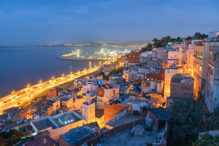 Aerial night view of Tangier city by the water with glowing lights